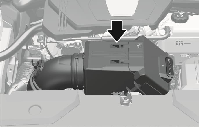 2025 Genesis GV70 air cleaner filter housing image. A black arrow points downward to the top of the air cleaner cover located in the engine compartment. The cover features a handle on the right side with the text 'PULL OUT TO OPEN'. This explains the location of the air cleaner filter for replacement.