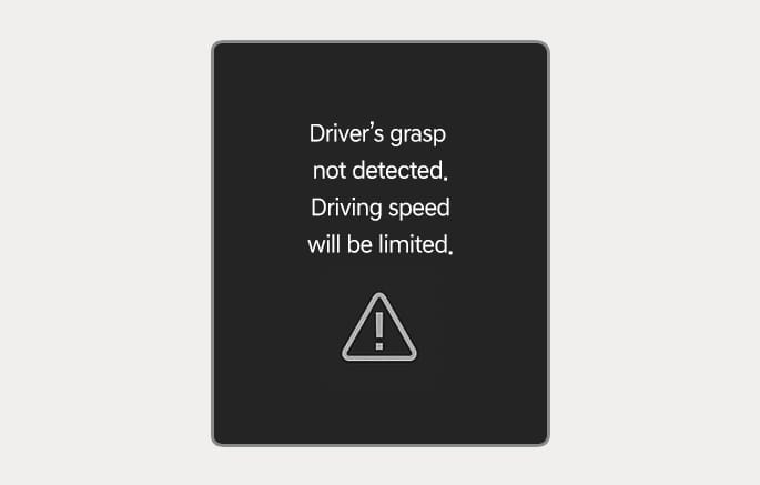 2025 Genesis GV70 instrument cluster warning message image. It displays the text 'Driver's grasp not detected. Driving speed will be limited.' above a triangle warning icon with an exclamation mark. This explains the function that limits driving speed when the driver does not hold the steering wheel.