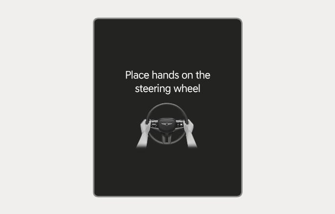 2025 Genesis GV70 hands-off warning message image. The display shows the text 'Place hands on the steering wheel' above a graphic of hands gripping a wheel. Explains the warning function displayed when the driver releases the steering wheel.