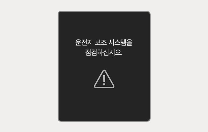 2025 제네시스 GV70 클러스터 경고 메시지 이미지입니다. 검은색 배경의 화면 중앙에 흰색 텍스트로 '운전자 보조 시스템을 점검하십시오.'라는 문구가 표시되어 있고, 하단에는 삼각형 안에 느낌표가 있는 경고등 아이콘이 있습니다. 운전자 보조 시스템에 이상이 발생했을 때 점검을 안내하는 화면 구성을 설명합니다.