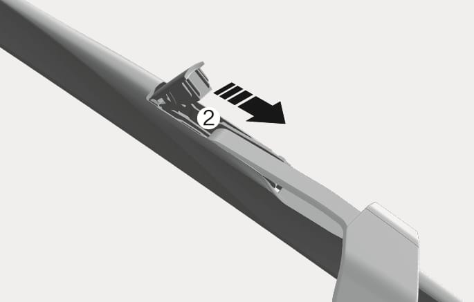 2025 제네시스 GV70 앞유리 와이퍼 블레이드 분리 이미지입니다. 와이퍼 암 연결 부위에서 숫자 (2)와 검은색 화살표가 블레이드를 아래로 미는 방향을 나타냅니다. 잠금 커버를 연 상태에서 블레이드를 아래로 밀어 분리하는 방법을 설명합니다.